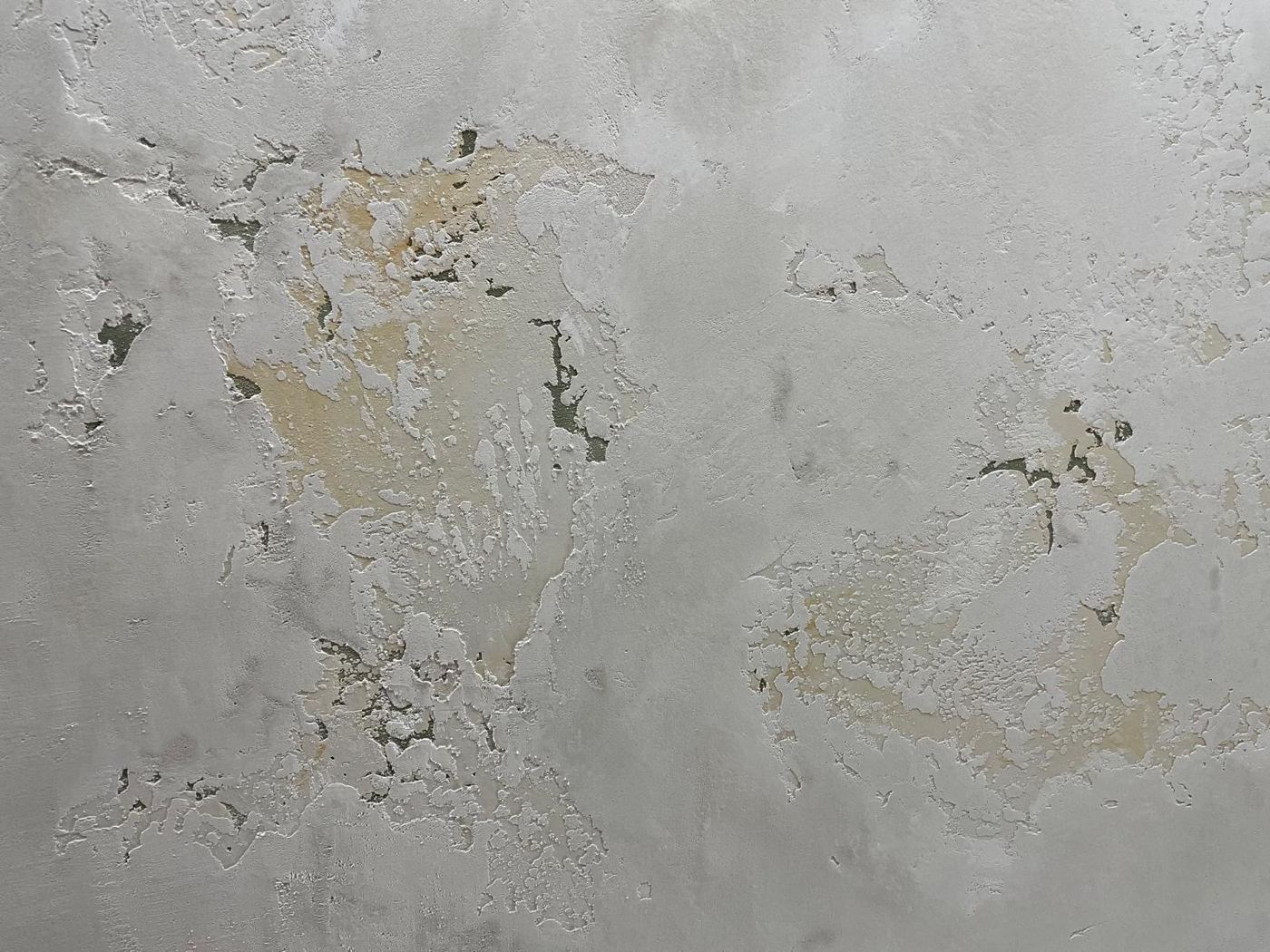 Enduit patiné gris clair laissant apparaître des couches ocre et vertes