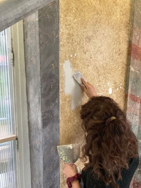 Félicie rebouche une lacune dans un enduit décoratif